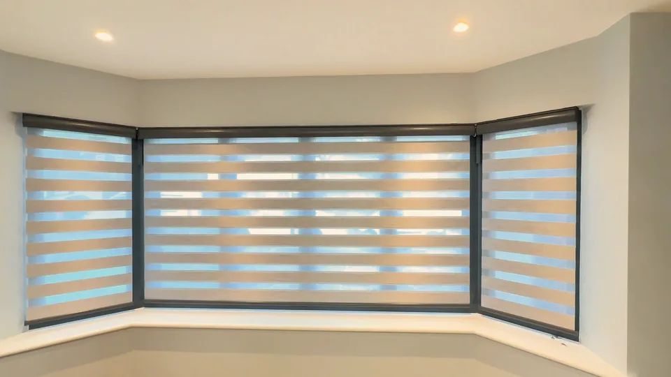 Bay window with the blinds lowered and sheer bands aligned, daylight showing through in stripes.