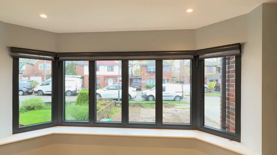 Bay window with the day and night blinds fully raised and the street outside in view.